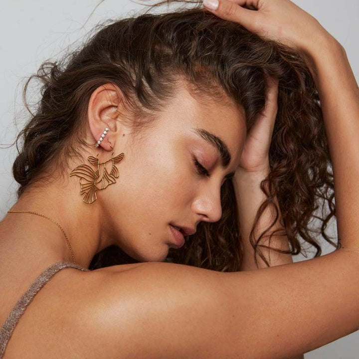 Polar Jewelry Guldpläterade Koi Hoops visas på kvinnor med vågigt hår, eleganta guldfärgade örhängen. Modell Koi-HP-GD-00101-2