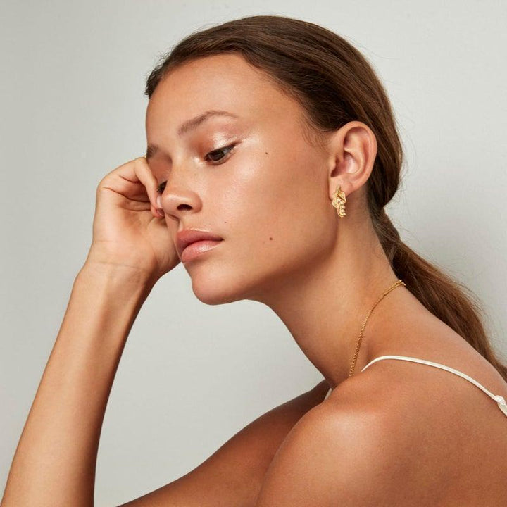 The Princess on the Pea örhänge som bärs av modell, visad i guldton, elegant och modern. Modell pri-st-gd-wz-00310-2