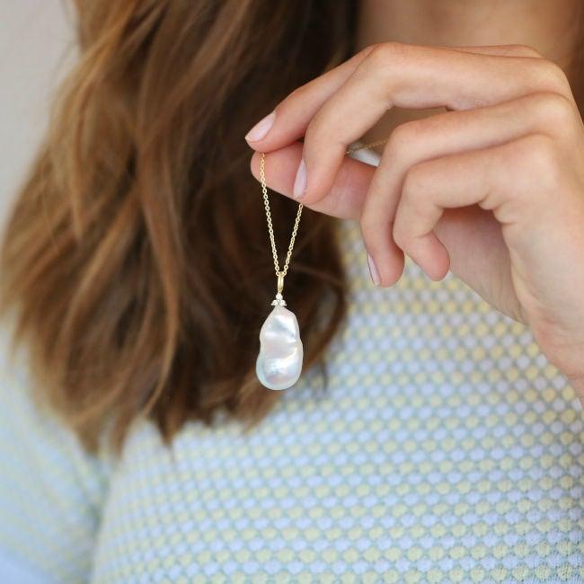 ro copenhagen 18kt joy barock pärlhängande diamanter som visas i hand mot mönstrad jersey. Modell 108637-2