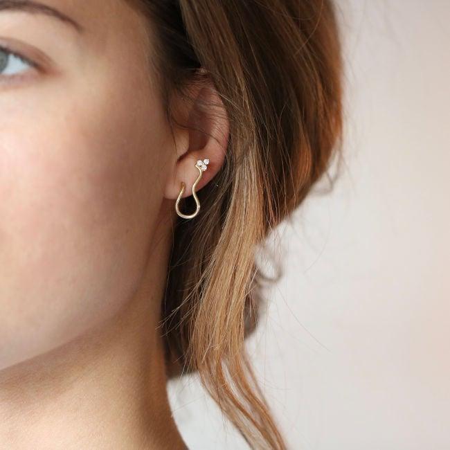 ro copenhagen 18 karat freyd wave diamantörhänge kvar på örat, elegant vågigt guld och diamantdesign. Modell 108104-2