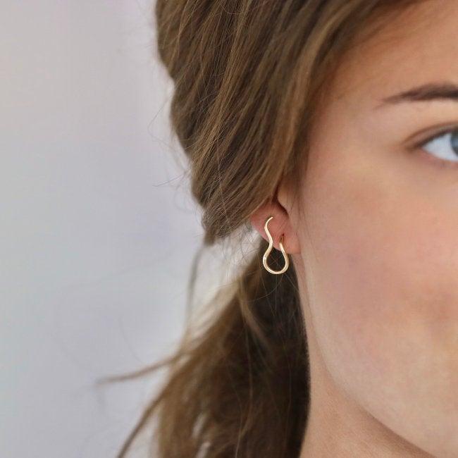 Ro Copenhagen 18kt Fryd Wave örhängen ses i vänster öra, eleganta i vågformat guld. Modell 108102-2